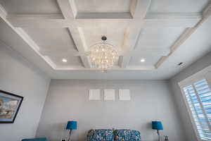 Detailed view of a chandelier, ornamental molding, and coffered ceiling