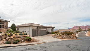 Mediterranean / spanish-style house featuring stone siding, stucco siding, a mountain view, and a garage