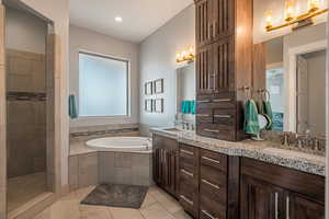 Bathroom featuring double vanity, a garden tub, light tile patterned floors, and tiled shower
