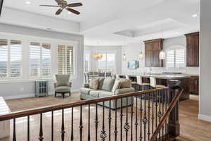 Living area with a tray ceiling, ceiling fan, ornamental molding, hanging lights, and a mountain view