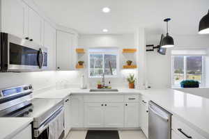 casita Kitchen with stainless steel appliances, open shelves, white cabinetry, and pendant lighting