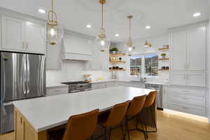 Kitchen with stainless steel appliances, pendant lighting, backsplash, and dual tone cabinetry