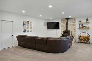 down stairs Living area featuring light carpet, recessed lighting, and a wood stove