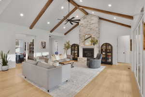 Living room with light wood-style flooring, a large fireplace, ceiling fan, and recessed lighting