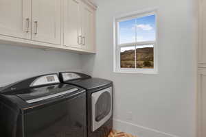 Laundry room featuring cabinet space, brick floors, and independent washer and dryer