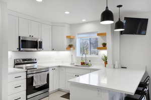 Casita Kitchen featuring open shelves, stainless steel appliances, a breakfast bar, and white cabinets