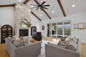 Living area with a fireplace, light wood finished floors, vaulted ceiling, and ceiling fan