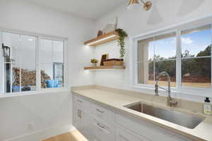 down stairs Kitchenette with open shelves, white cabinetry, plenty of natural light, and light stone countertops