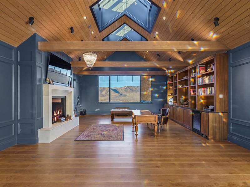 Dining area with a lit fireplace, wine cooler, dark wood finished floors, and a high wooden ceiling