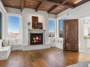 Living area featuring a premium fireplace, a wooden ceiling with exposed beams, hardwood / wood-style flooring, healthy amount of natural light, and recessed lighting