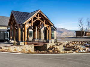 View of front facade with a standing seam roof, covered porch, stone siding, and a mountain view