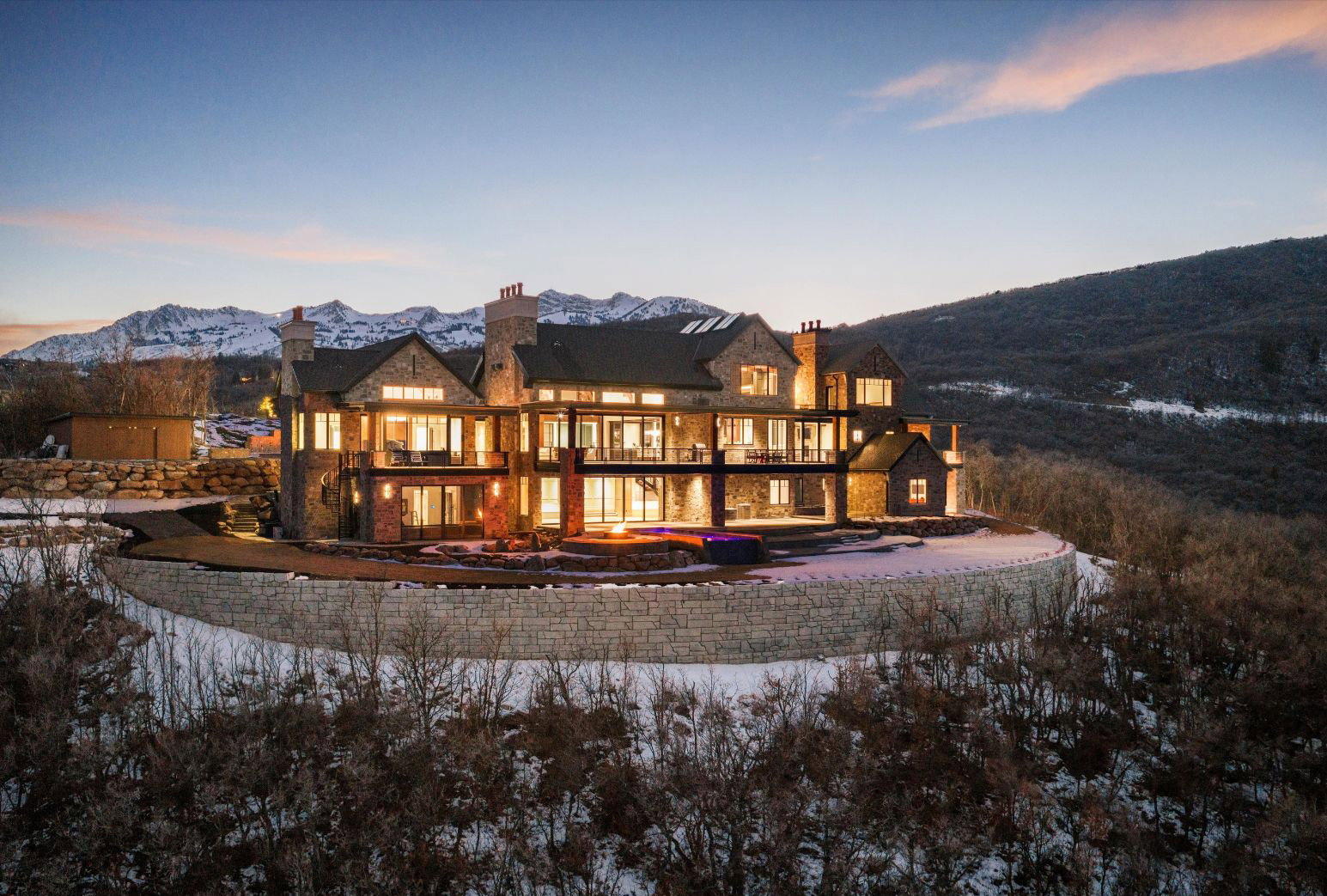 Snow covered back of property featuring a chimney, a mountain view, and a patio