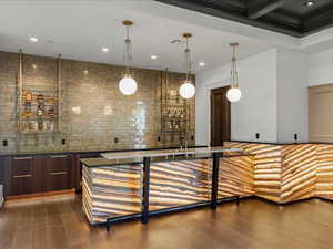 Bar area featuring modern cabinets, pendant lighting, dark wood finish cabinetry, and dark stone countertops