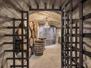 Wine room with concrete flooring, suspended lighting, and wooden ceiling
