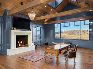 Office space featuring a warm lit fireplace, a wood ceiling with exposed beams, and hanging lights
