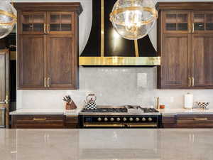 Kitchen featuring glass fronted cabinets, decorative backsplash, range with two ovens, pendant lighting, and light stone countertops