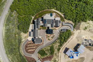 Expansive property featuring a multi-structure residence with dark-toned roofing, a swimming pool, and extensive paved driveways