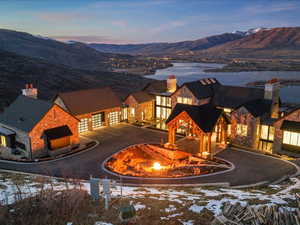 Snow covered building featuring a water and mountain view, a garage, and curved driveway