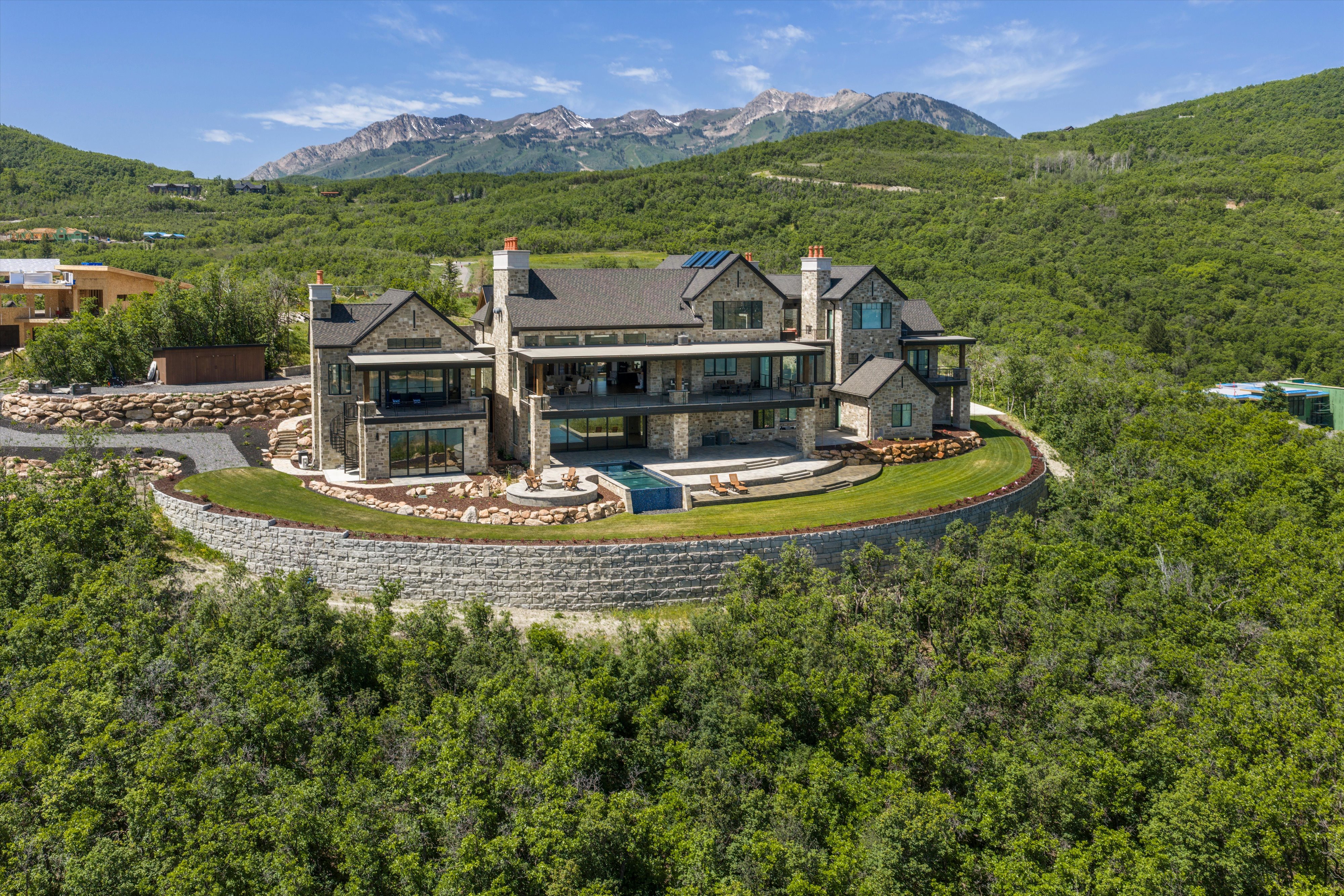 Stone and glass contemporary residence featuring multiple balconies and terraces