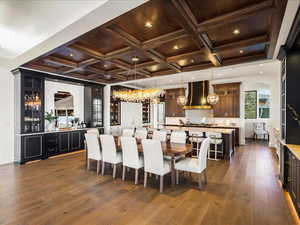 Dining area with coffered ceiling, dark wood-style floors, arched walkways, and crown molding