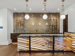 Indoor wet bar featuring dark wood finish cabinets, hanging light fixtures, and modern cabinets