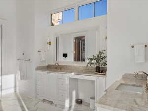 Bathroom with vanity, a high ceiling, and light marble finish flooring