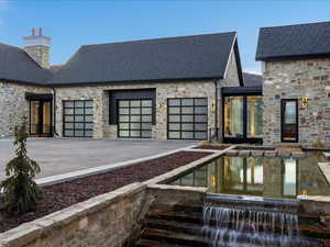 View of front of home featuring stone siding, an attached garage, and a chimney