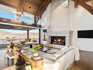 Living area with a high end fireplace, hardwood / wood-style floors, and a high wood beamed ceiling