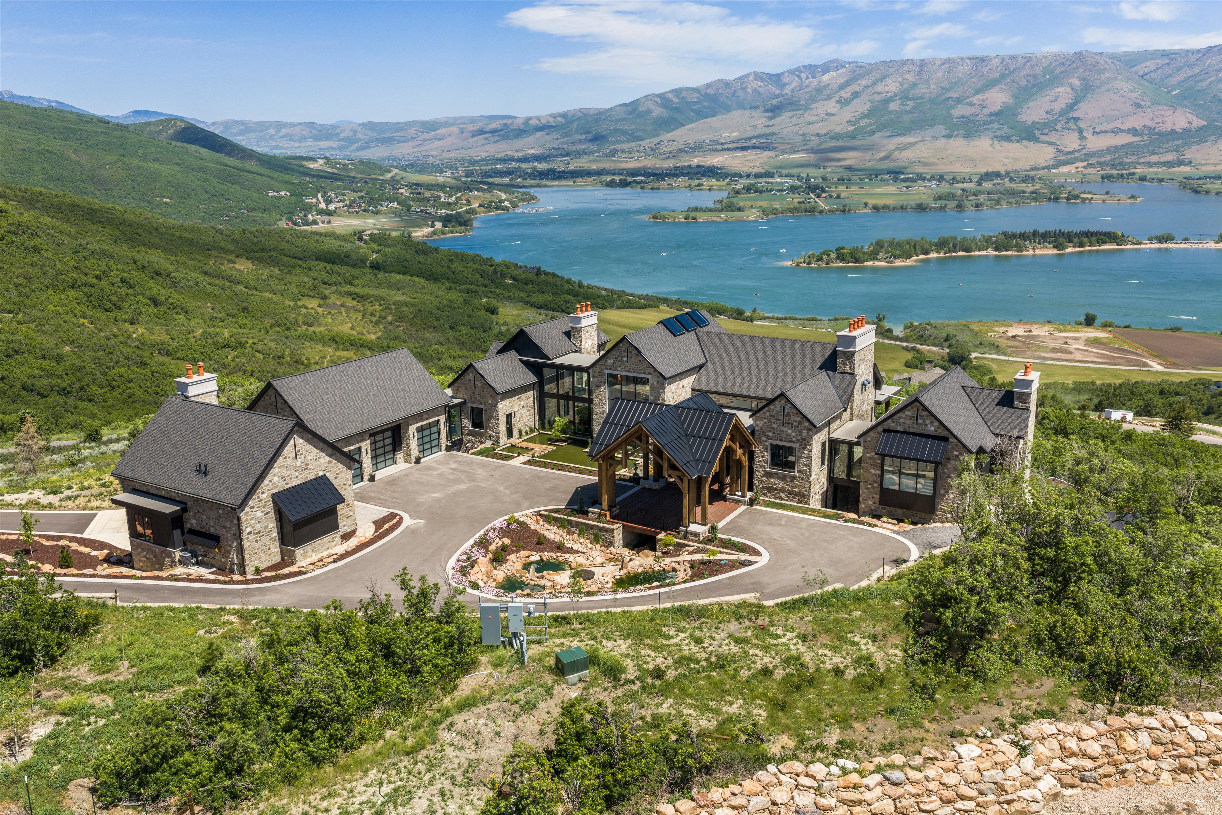 Hillside property featuring a stone and siding exterior, multi-gabled roofline, and a paved circular driveway