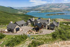 Hillside property featuring a stone and siding exterior, multi-gabled roofline, and a paved circular driveway