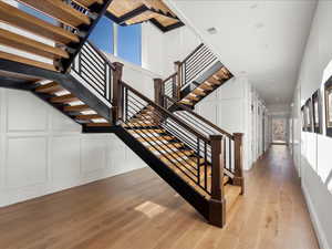 Staircase with a decorative wall and hardwood / wood-style floors