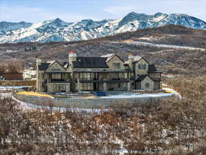 Snow covered house with a chimney, stone siding, and a mountain view