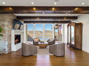Living room featuring plenty of natural light, a glass covered fireplace, hardwood / wood-style floors, and beam ceiling