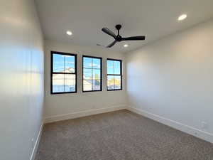 Empty room featuring ceiling fan, dark carpet, and recessed lighting