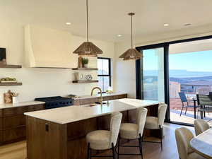 Kitchen featuring open shelves, black gas stove, decorative light fixtures, and light wood-style flooring