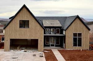 View of front of home with an attached garage, concrete driveway, and a porch