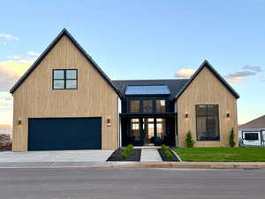View of front of house featuring french doors, a garage, concrete driveway, a standing seam roof, and covered porch