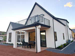 Back of property at dusk with a patio, outdoor dining space, and stucco siding