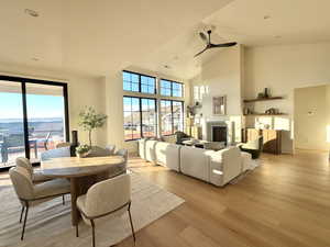 Dining space with a ceiling fan, light wood-style floors, lofted ceiling, a fireplace, and recessed lighting