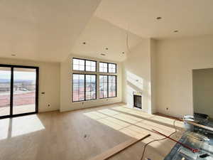 Unfurnished living room with a fireplace, light wood-style flooring, and vaulted ceiling