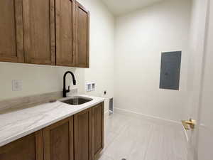Laundry area featuring hookup for an electric dryer, electric panel, cabinet space, washer hookup, and light tile patterned floors
