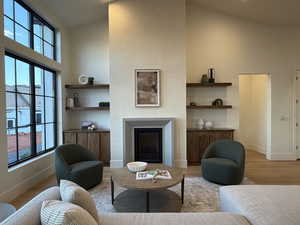Living area featuring wood finished floors, a fireplace, lofted ceiling, and built in shelves
