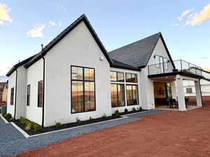 Rear view of house with stucco siding, a patio area, and outdoor dining space