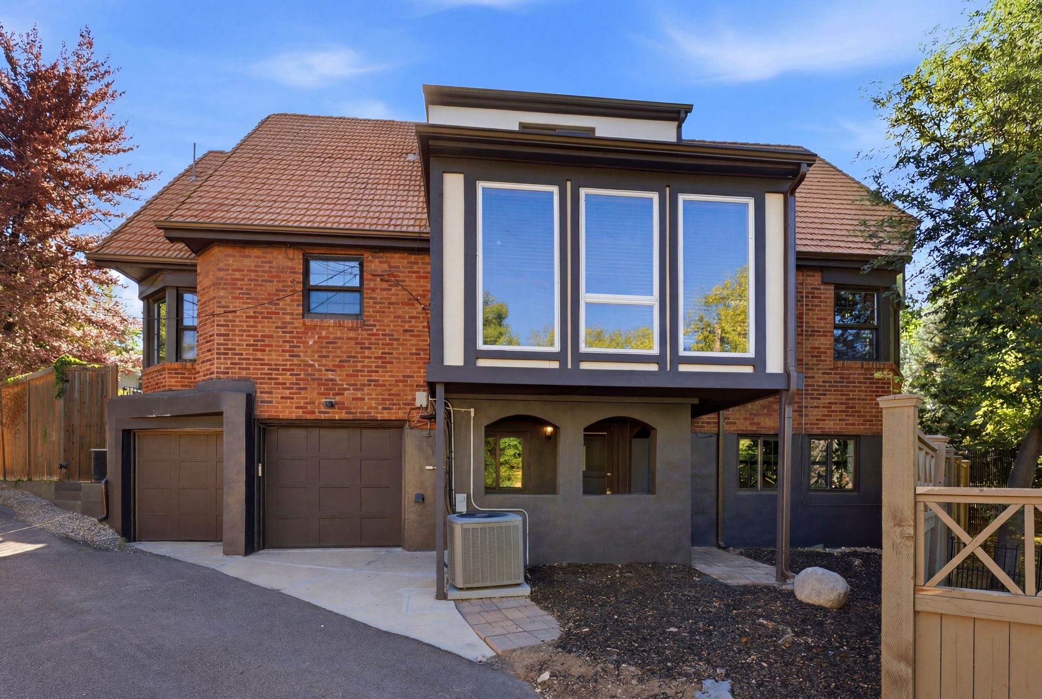 Brick and stucco exterior featuring a red tile roof and multiple window styles