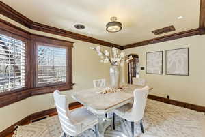 Dining area with arched walkways, wood finished floors, and crown molding