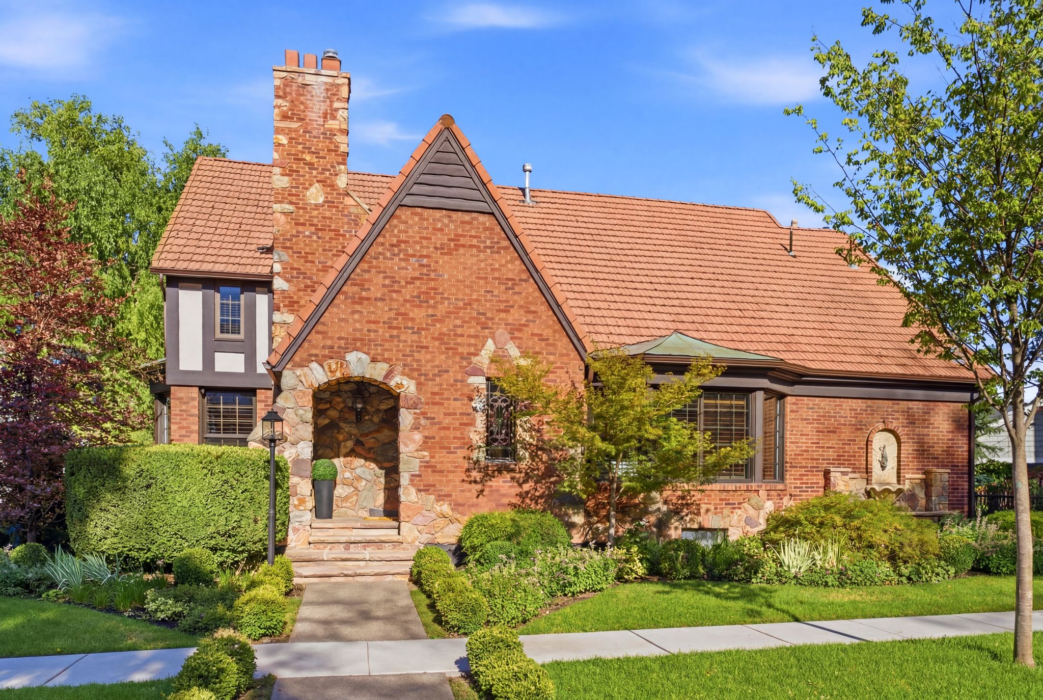 Brick and stone exterior with a prominent arched entry and a terracotta tile roof