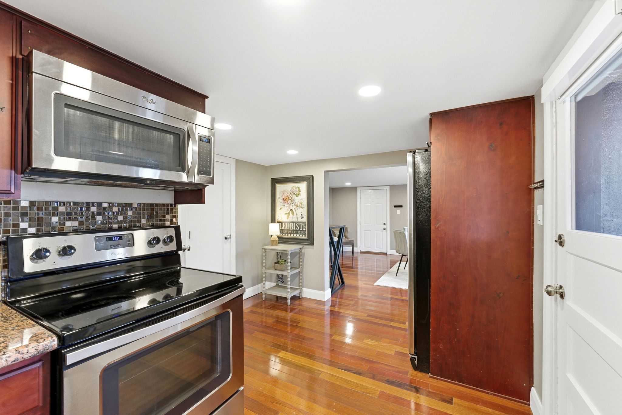 Kitchen featuring stainless steel appliances, dark wood-style floors, recessed lighting, light stone counters, and reddish brown cabinets