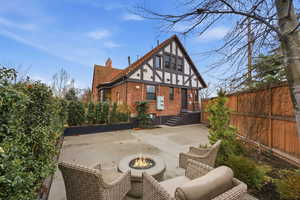 Rear view of house featuring brick siding, a fenced backyard, a chimney, a fire pit, and a patio
