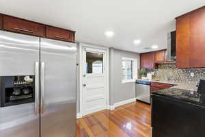 Kitchen featuring stainless steel appliances, light stone counters, decorative backsplash, recessed lighting, and light wood-type flooring