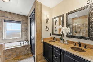 Full bathroom with a garden tub, stone tile flooring, double vanity, tiled shower, and tile walls